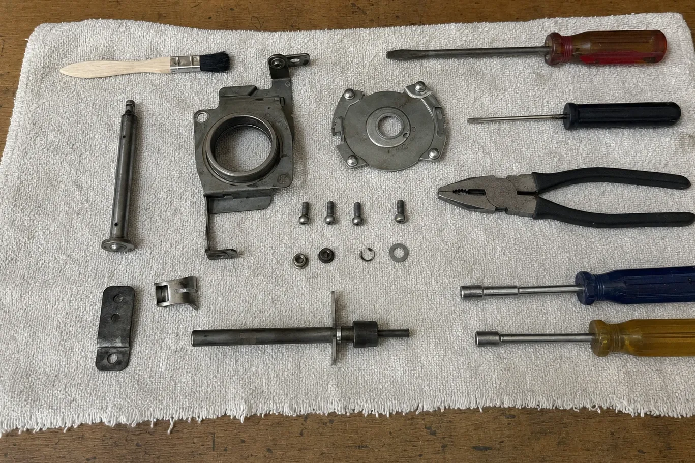 Ventilation blower motor stripped down: bearing housing, mount plate, shaft with a rubber-bushed hub, screws and brush